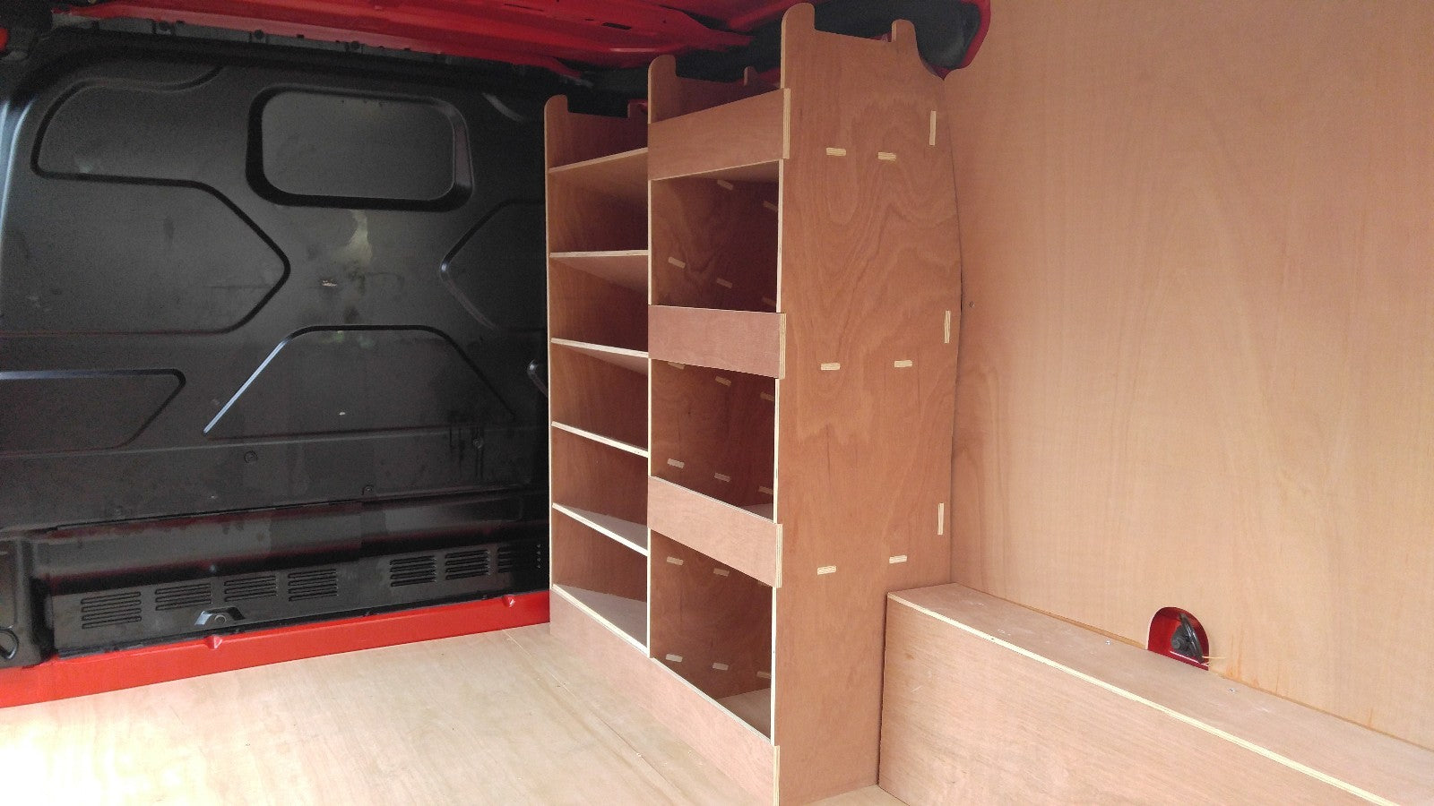 Ford Custom van racking with plywood shelving and deep storage drill/service case in a commercial vehicle.
