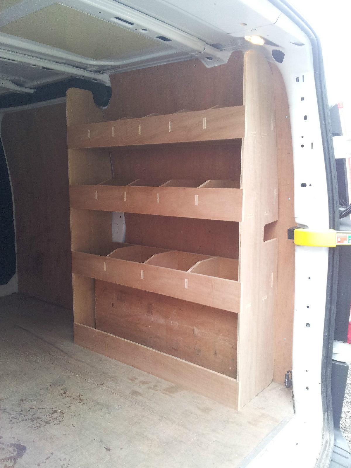 Plywood tool storage rack installed in a Transit Custom SWB van, featuring multiple shelves for organized van interior storage.